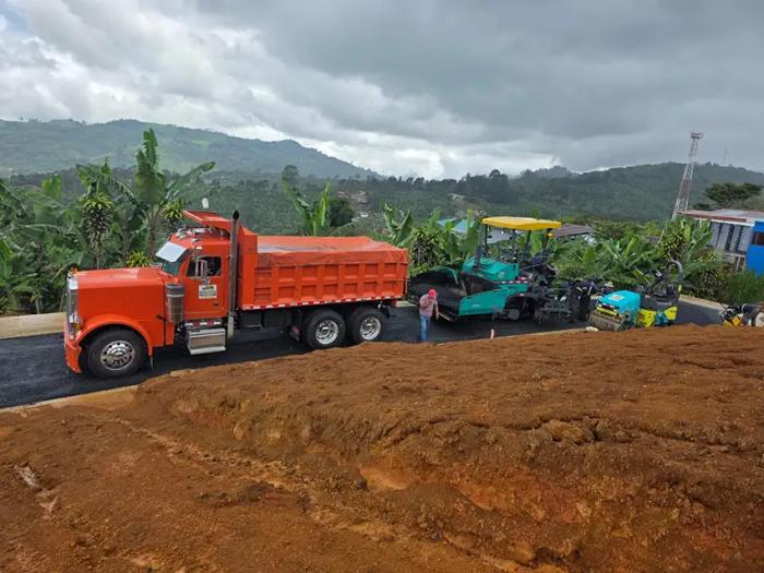 Pavimentación y colocación de asfalto con maquinaria pesada en carretera de zona montañosa.