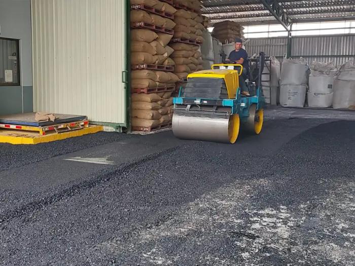 Compactado de capa asfáltica con rodillo en accesos y patios de bodega industrial.