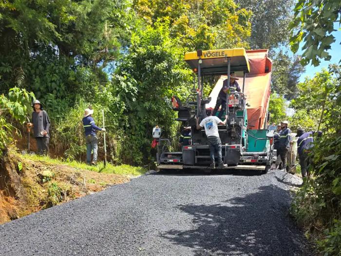 Pavimentadora Vögele y equipo de trabajadores colocando carpeta asfáltica en camino rural rodeado de