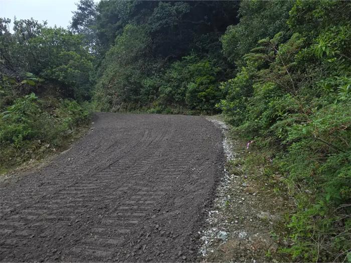 Conformación, nivelación y compactación de base granular en camino rural de montaña.