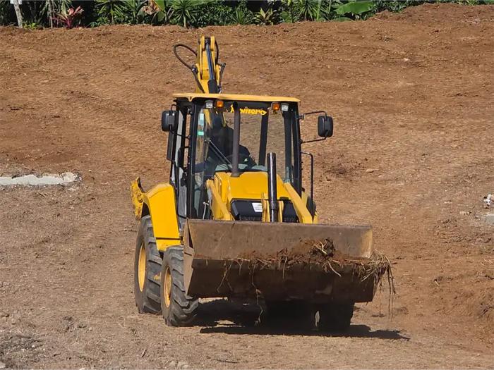 Retroexcavadora realizando labores de excavación, carga y nivelación de terreno.
